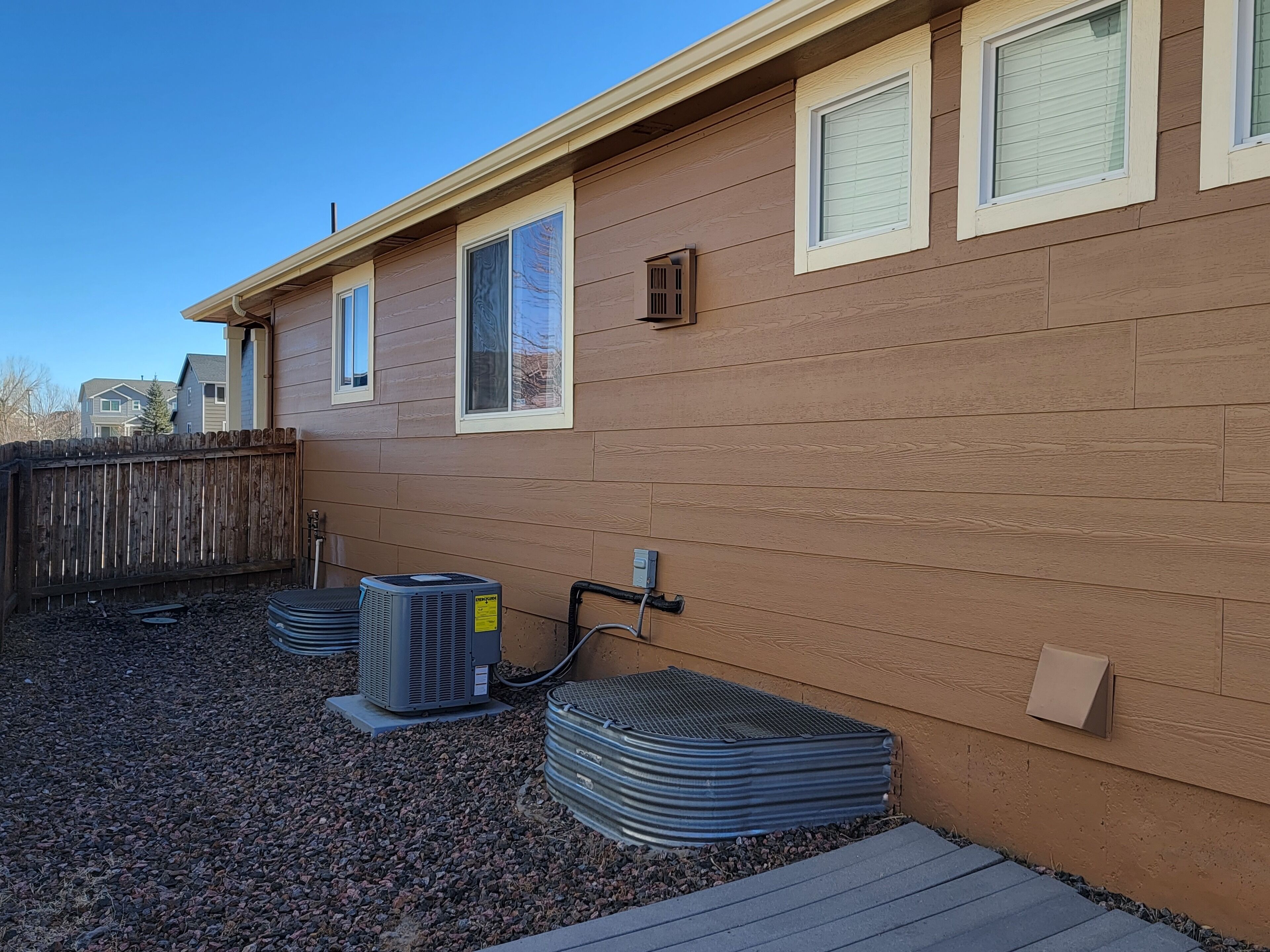 A residential building with a brown exterior, multiple windows, and a wooden fence.