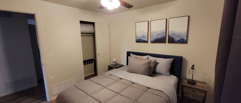 A bedroom with a bed, a ceiling fan, a nightstand, a lamp, and a closet.