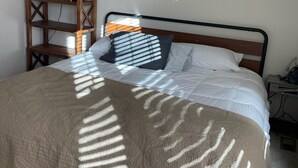 A bedroom with a bed, a wooden shelving unit, and a bedside table.