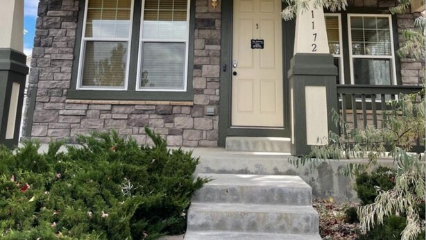 A two-story house with a stone facade, a front porch, and a mailbox.