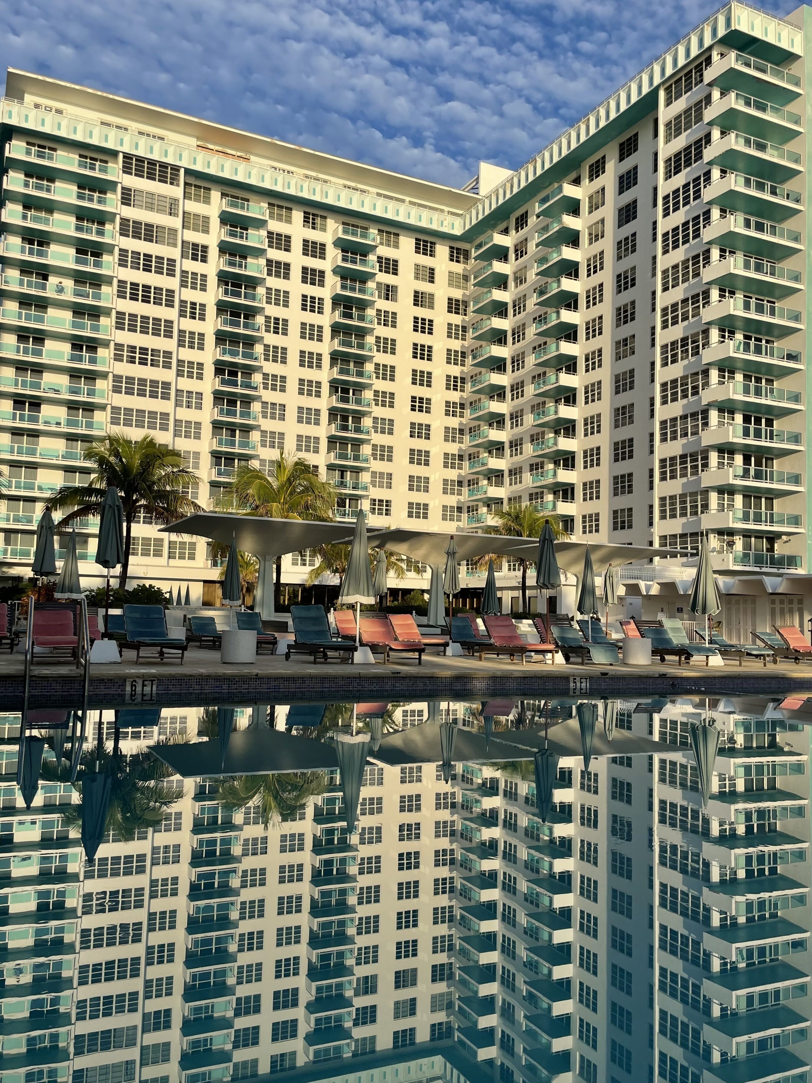 A high-rise hotel with a swimming pool, multiple balconies, and outdoor seating areas.