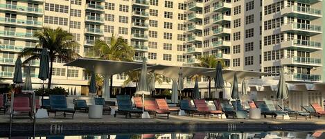 A high-rise hotel with a swimming pool, multiple balconies, and outdoor seating areas.