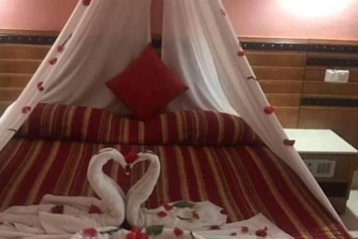 A bed with a canopy, red pillows, and a heart-shaped decoration on the bedspread.