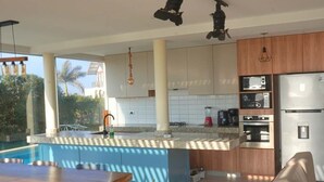 Una cocina moderna con una isla grande, electrodomésticos integrados y un comedor con vistas a la piscina.