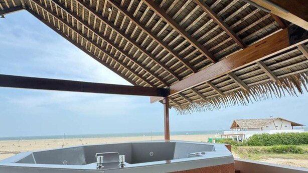 Un baño moderno con una bañera de madera, zona de ducha y vistas a la playa.