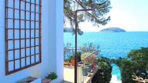 A balcony with a view of the sea and a distant island.
