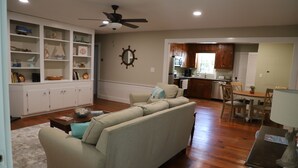A living room with a sectional sofa, a coffee table, and a bookshelf filled with decorative items. - 6 Bed/4 Bath whole house duplex, minutes from golf, restaurants, and the beach! (Murrells Inlet)