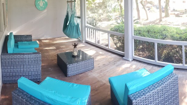 A sunlit room with wicker furniture, a hanging hammock, and a view of greenery outside. - 6 Bed/4 Bath whole house duplex, minutes from golf, restaurants, and the beach! (Murrells Inlet)