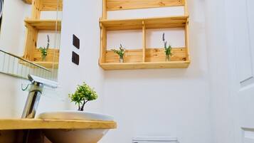 Une salle de bain avec un meuble-lavabo en bois, des toilettes blanches et des étagères en bois ornées de plantes.