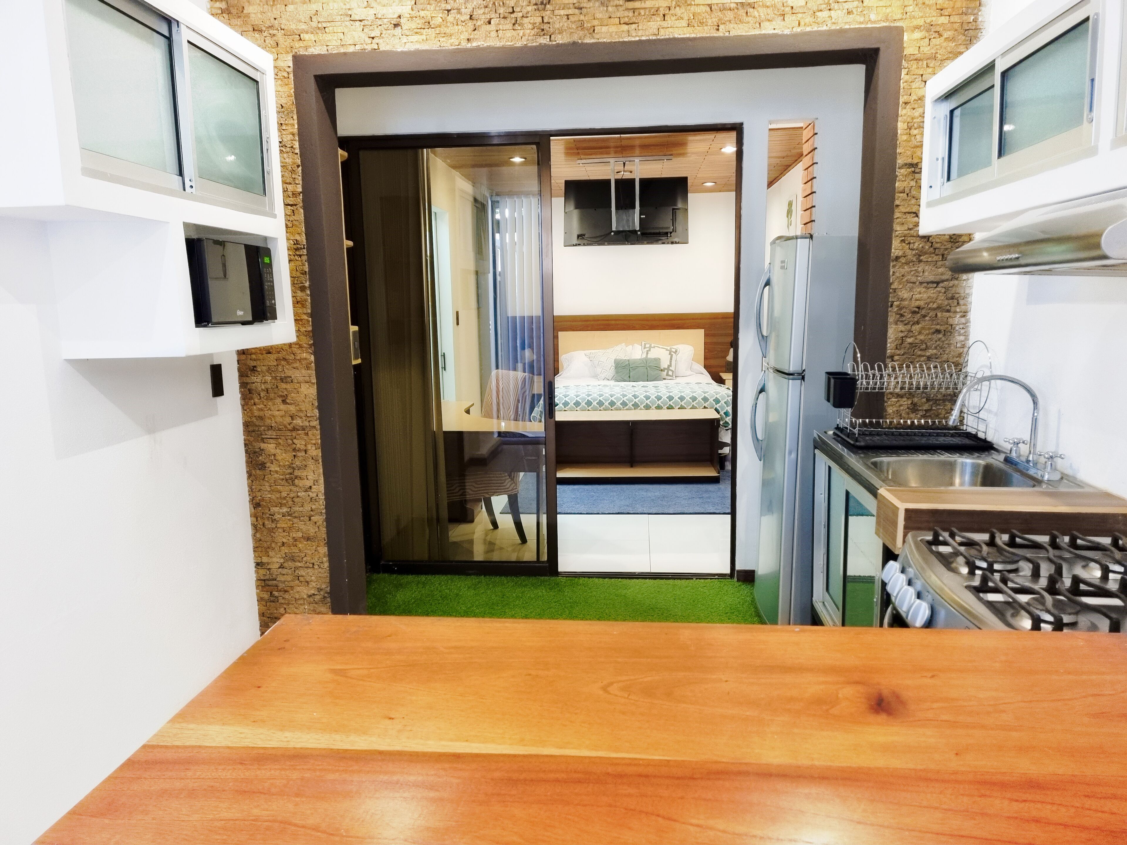 A compact room with a kitchenette, a bed with a view, and a small seating area.