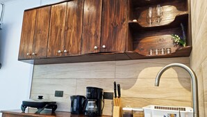 A kitchen with wooden cabinets, a stainless steel sink, a microwave, a coffee maker, and a knife block.