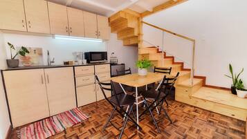 A modern kitchen with wooden cabinets, a dining table with chairs, a microwave, and a coffee maker.