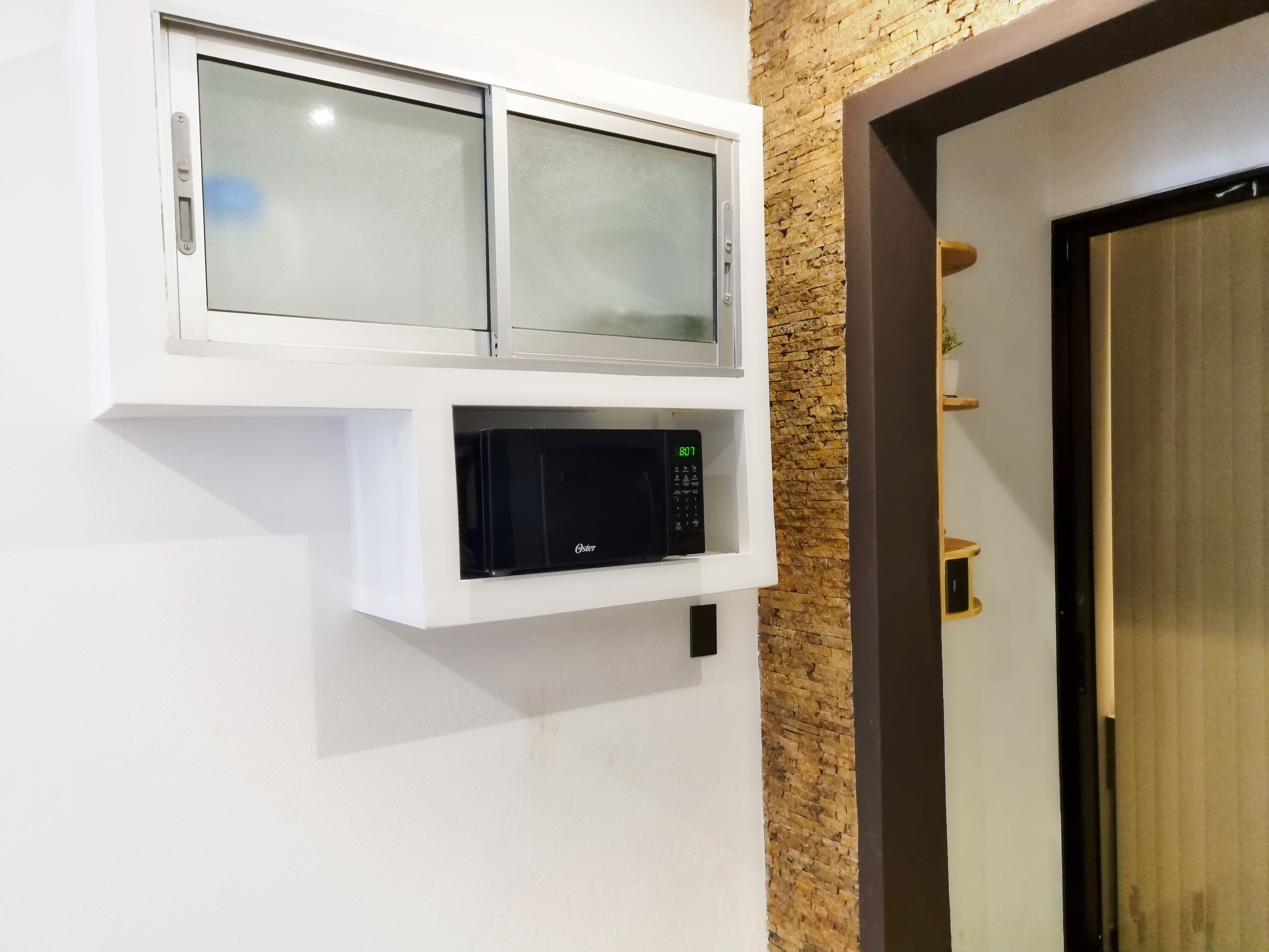 A wall-mounted microwave and oven in a kitchen area.