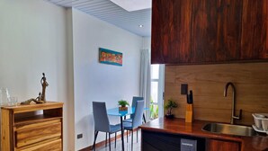 A modern kitchen with a wooden countertop, a sink, and a dining area with chairs and a table.