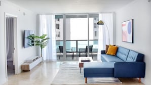Una sala de estar moderna con un sofá azul, una mesa de centro y un ventanal con vistas a un edificio.