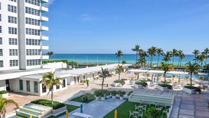 A resort with a pool area, outdoor seating, and a view of the ocean. - 2bd2bth Partial Ocean view Ste w/ balcony, Pool, nearby dining, beach access (Miami Beach)