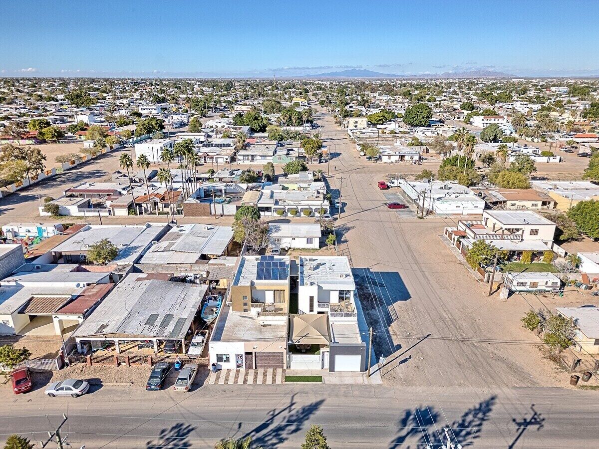 Vista aérea de una zona residencial con casas, calles y cielo despejado.