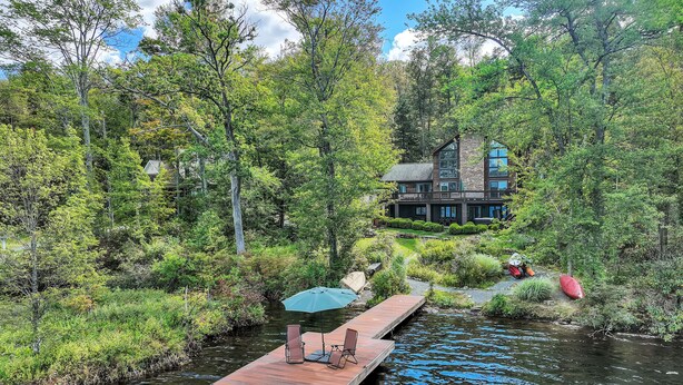 A wooden dock extending into a river, surrounded by lush greenery and trees.