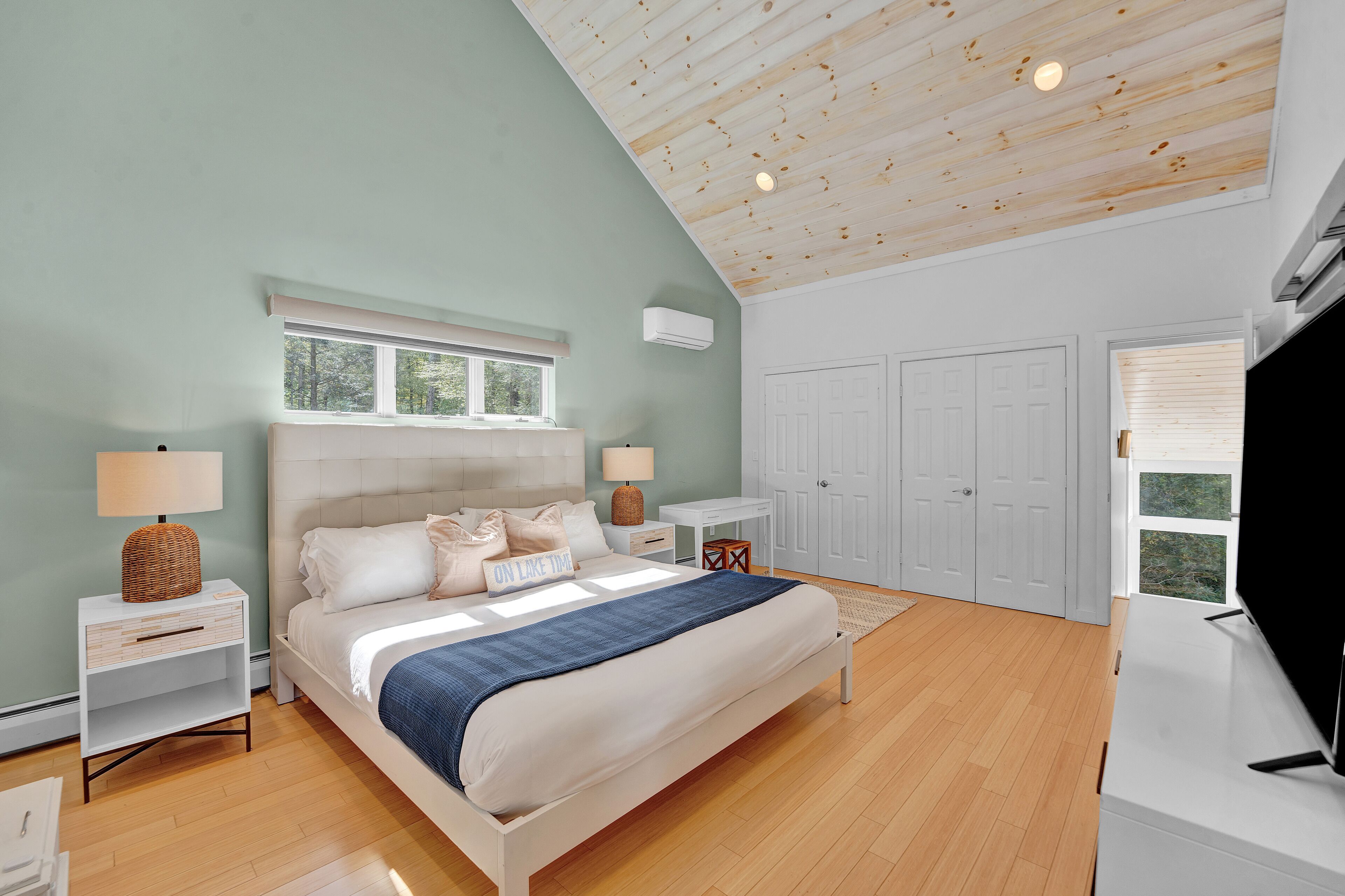 Une chambre à coucher comprenant un lit, des tables de chevet, une commode, un téléviseur et une armoire.