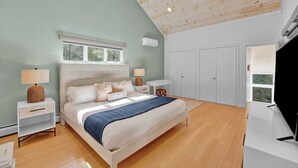 A bedroom with a bed, bedside tables, a nightstand, a TV, and a wardrobe.