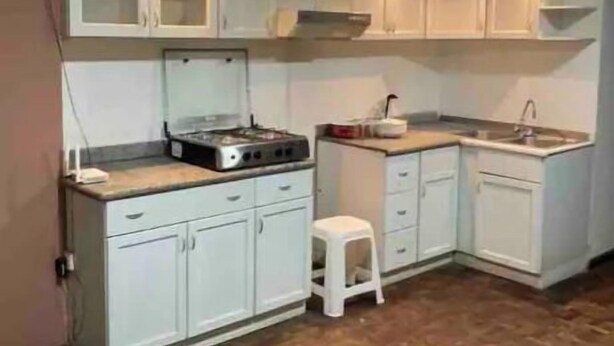 Una cucina compatta con mobili bianchi, un piano di lavoro, un fornello e un lavello.