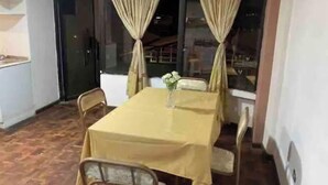 Zona pranzo con tavolo imbandito per quattro, tende e finestra con vista.