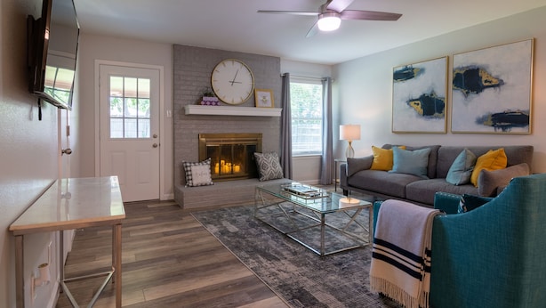 A modern living room with a fireplace, a sofa, a coffee table, and a television mounted on the wall.