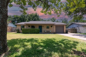 A two-story house with a front yard, a garage, and a tree. - Quiet & Cozy in Georgetown, TX-Pets-Long Stays-Office (Georgetown)