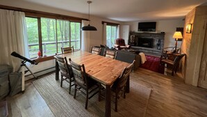 Un comedor con una mesa y sillas de madera, una chimenea y un televisor fijado a la pared.