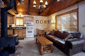 A cozy living room with a fireplace, wooden furniture, and a dining area with a table and chairs. - Serene retreat is just steps to the National Forest (Big Bear)