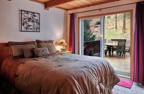 Una camera da letto con un letto grande, un comodino, una lampada e vista su un patio esterno con tavolo e sedie.
