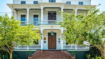 Stately building with a central entrance and double doors, surrounded by a white picket fence.