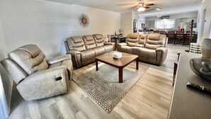 A living room with leather sofas, a coffee table, and a dining area in the background.