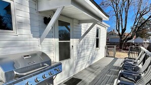 A barbecue grill and outdoor seating area on a wooden deck.
