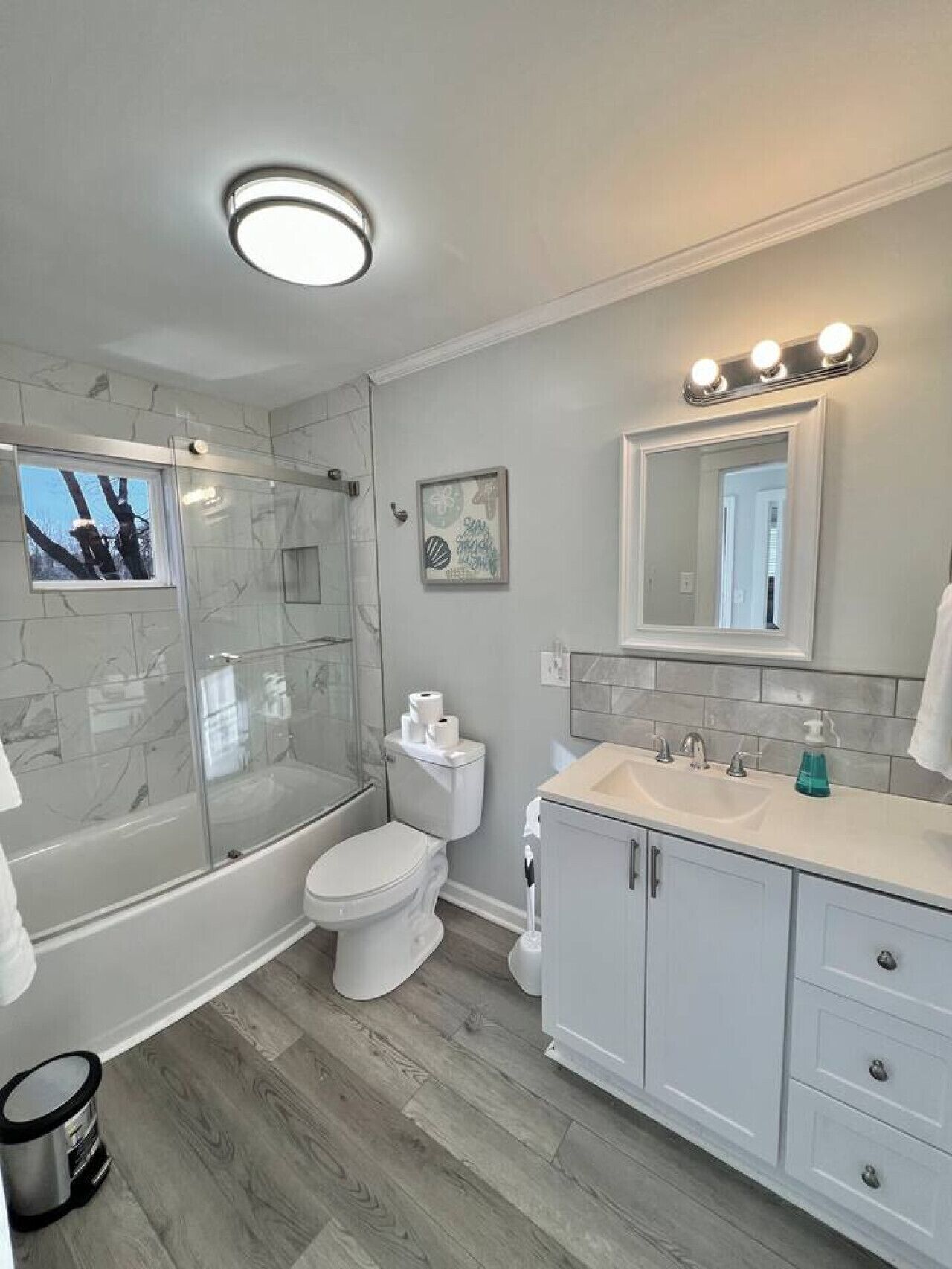 A modern bathroom with a glass-enclosed shower, a toilet, a sink with a mirror, and a vanity with cabinets.