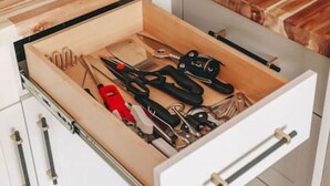 A kitchen with a wooden countertop, a microwave, and a drawer with various utensils. - The Fjäll | Ski-In Ski-Out Village Studio (Big White)