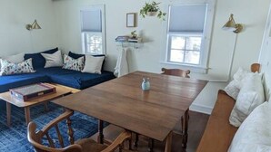 A cozy living room with a wooden dining table, blue sofa, and a blue rug.