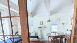 A spacious room with a wooden floor, a bed, a desk, and a chair.