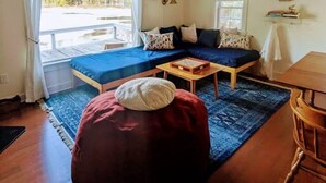 A cozy room with a bed, a sofa, a wooden table, and a bean bag.