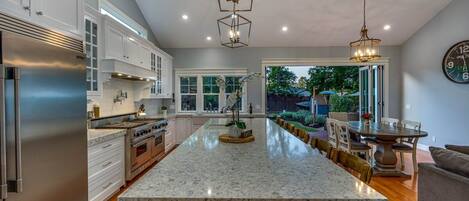 A spacious kitchen with a large island, stainless steel appliances, and a dining area with a table and chairs.