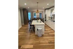 Kitchen features a central island with a countertop, white cabinetry, and a stainless steel range hood.