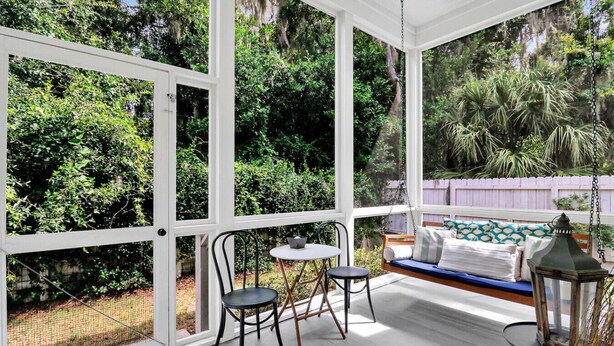 Un patio couvert avec un banc en bois, deux chaises et une table.