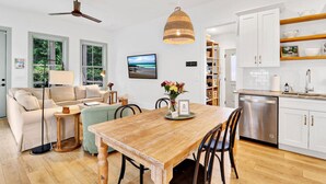 Un salon moderne avec une table à manger en bois, un canapé et un ventilateur de plafond.