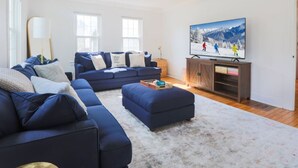 Una sala de estar moderna con un sofá seccional, un televisor de pantalla plana y un mueble de madera.