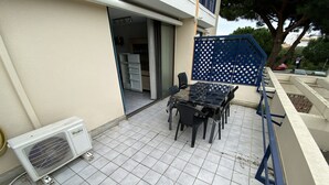 An outdoor patio with a table and chairs, a white air conditioning unit, and a blue gate.