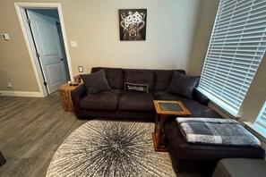 Ein Wohnzimmer mit einem dunkelbraunen Sofa, einem runden Teppich und einem kleinen Holztisch.