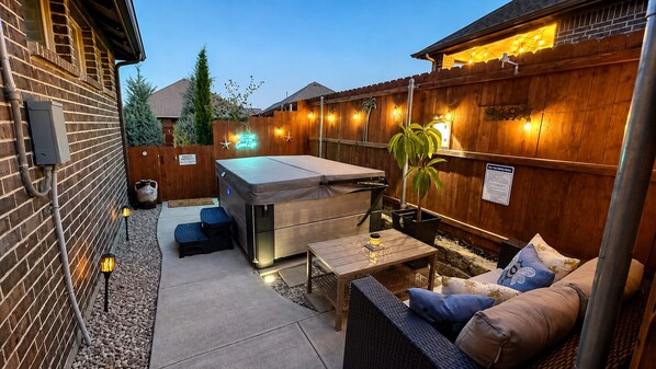 A backyard patio with a barbecue grill, outdoor seating, and string lights.