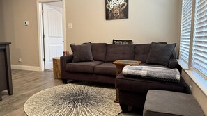 A living room with a brown sofa, a round rug, and a side table.