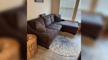 A modern living room with a sectional sofa, a round rug, and a wooden side table.