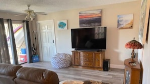 Ein Wohnzimmer mit einem braunen Sofa, einem Fernseher auf einer Holzeinrichtung und Kunstwerken an den Wänden.